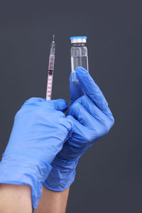 Midsection of woman holding syringe against black background