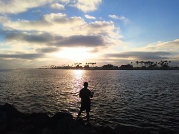 Silhouette man standing on beach against sky during sunset