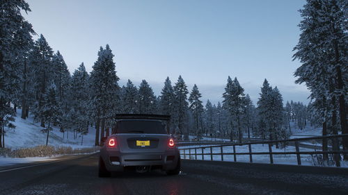 Car on road amidst trees in city against clear sky