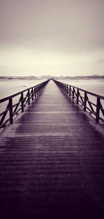 Surface level of wooden pier over sea against sky