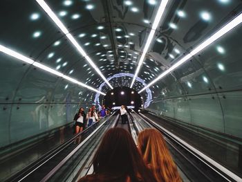 People on escalators against illuminated ceiling