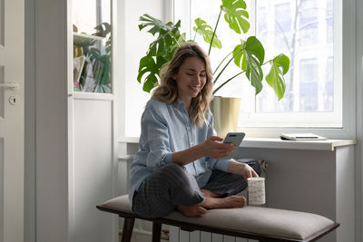 Woman using phone while sitting at home