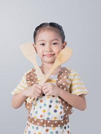 Portrait of cute girl holding camera over white background