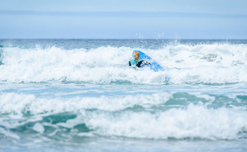 Woman surfing in sea against sky