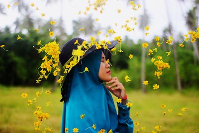 Woman standing on yellow flowering plants on field