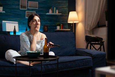 Young woman using mobile phone while sitting at home