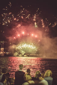 Firework display over sea against sky at night