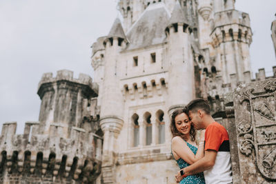 Couple embracing against historical building