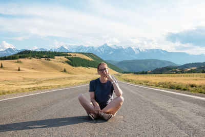 Portrait of man sitting on road against mountain
