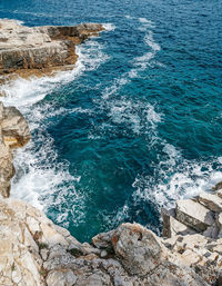 Rocky shoreline, blue sea, waves, copy space.