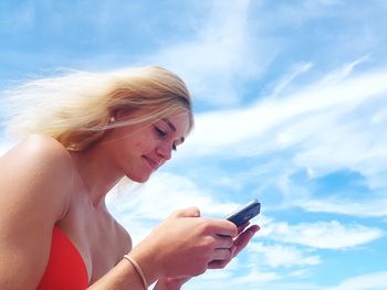 Side view of woman using mobile phone against sky