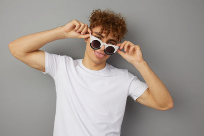 Man wearing sunglasses standing against gray background