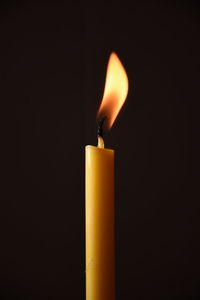 Close-up of lit candle in darkroom