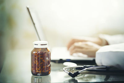 Close-up of hand holding glass jar on table