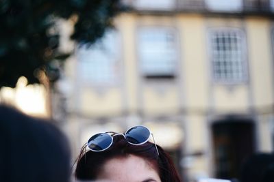 Cropped image of woman head wearing sunglasses against building outdoors