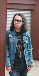 Portrait of young woman standing against wall