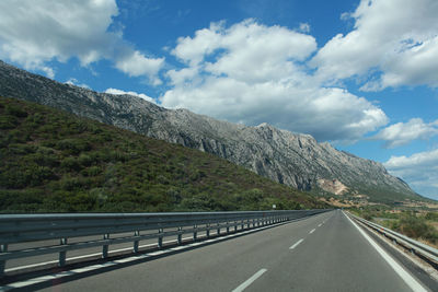 Road by mountains against sky