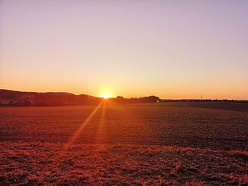 Scenic view of field against clear sky during sunset