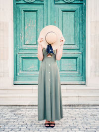 Woman with hat standing against door