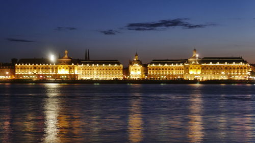 Illuminated buildings by river at night