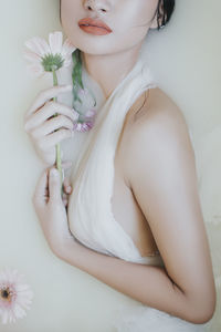 Midsection of woman holding flower against white background