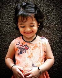 Portrait of cute girl smiling against wall