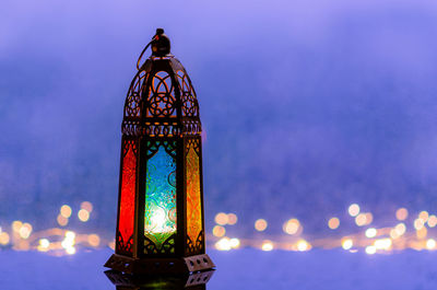 Lantern with lights decorating for islamic new year put at window with blurred blue background.