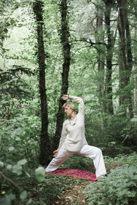 Senior woman doing yoga in the forest