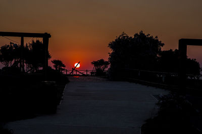 Silhouette man by trees against orange sky