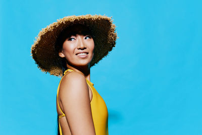 Portrait of young woman against blue background