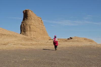 Woman on rock formations against sky