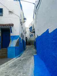 Narrow alley amidst buildings against blue sky