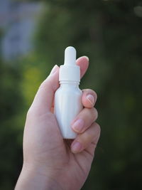 Close-up of hand holding white bottle