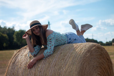 A beautiful young ukrainian woman lies on a hay bale and smiles