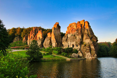 Rock formations by river against sky