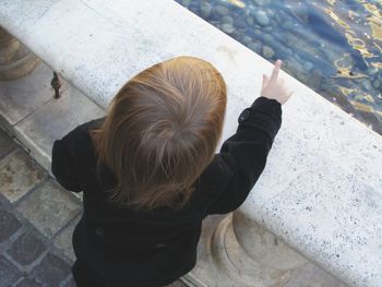 High angle view of child standing by pond