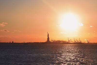 Silhouette of city at waterfront during sunset