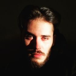 Close-up portrait of young man against black background