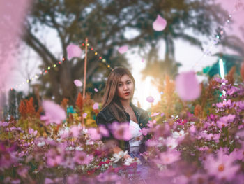 Portrait of woman with pink flowers against trees