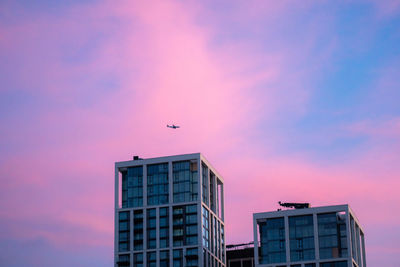Low angle view of airplane flying over buildings