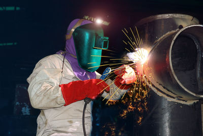 Midsection of man working at illuminated factory