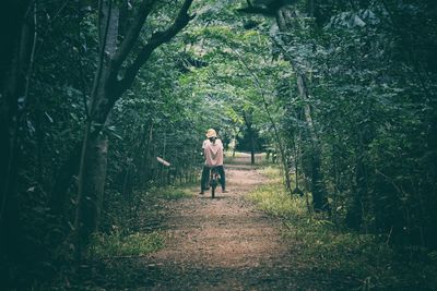 Rear view of man walking on footpath in forest