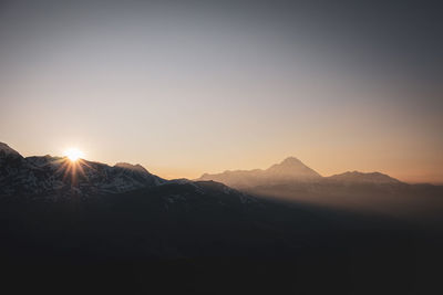 Scenic view of silhouette mountains against clear sky during sunset