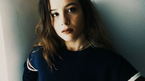 Portrait of beautiful young woman standing against wall