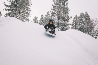 Boy starts down snowy hill on a sled.