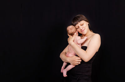 Happy woman standing against black background