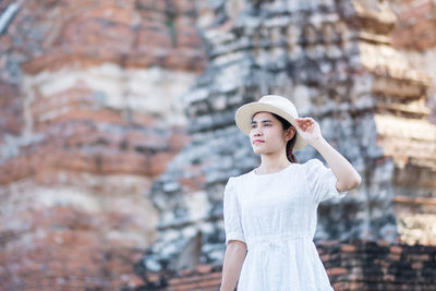 Portrait of young woman standing against blurred background