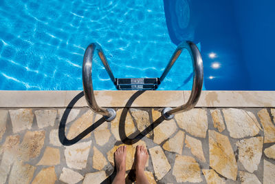 Low section of person standing by swimming pool
