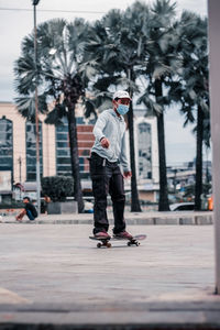 Full length of man skateboarding on street in city