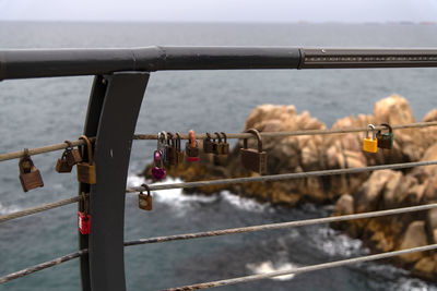 Close-up of padlocks on railing against sea